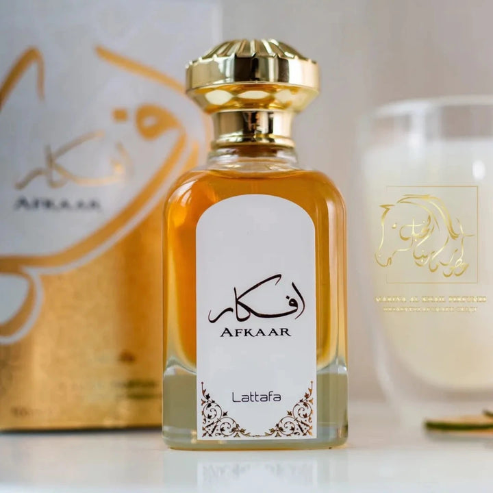 Perfume bottle with gold cap and white label featuring 'Afkaar' branding on a blurred background.