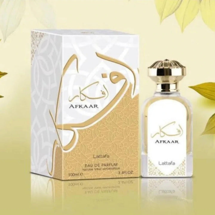 Atraar perfume bottle and packaging on a light yellow background with green leaves.