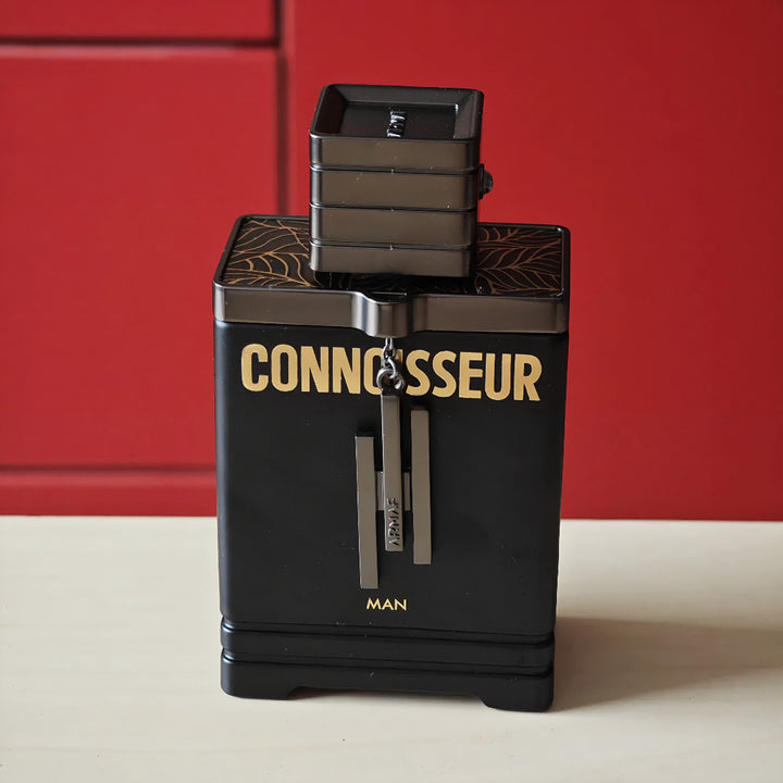Black and gold perfume bottle labeled 'Connoisseur' by MAN against a red background