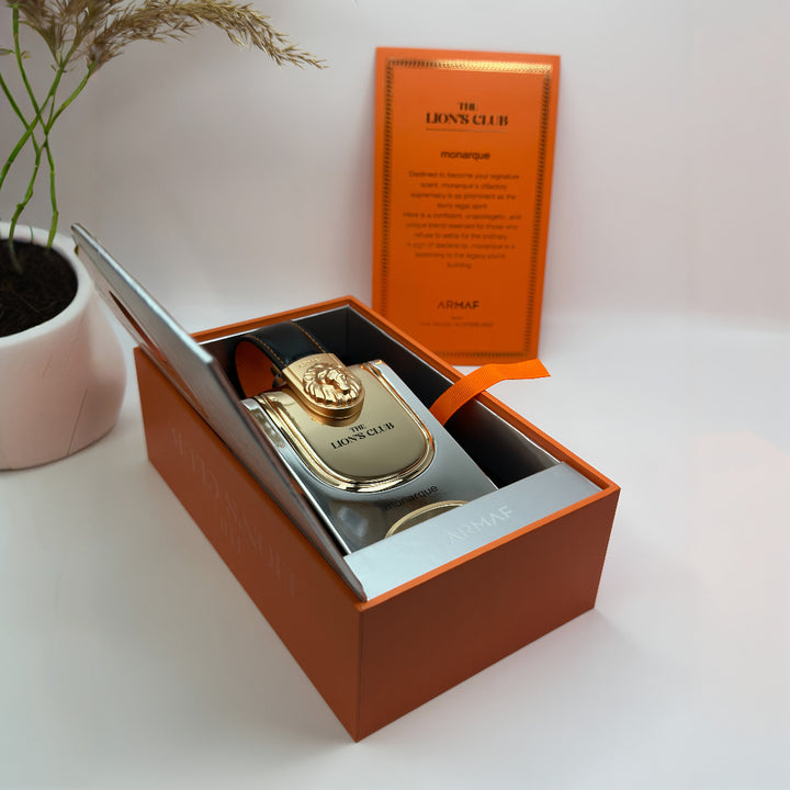 Perfume bottle with 'The Lions Club' branding in an open box on a white surface.