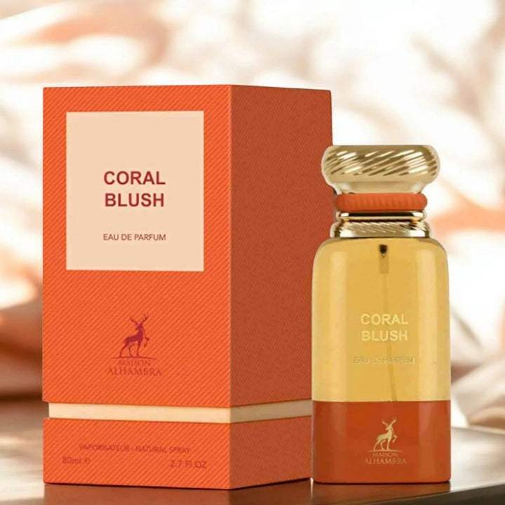 Coral Blush perfume bottle and packaging on a wooden surface with a blurred background.