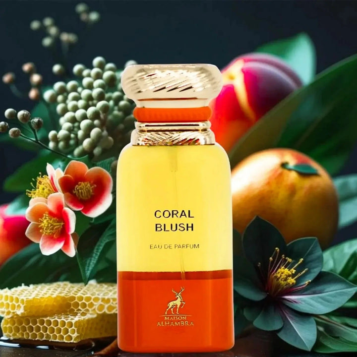 Perfume bottle labeled 'Coral Blush' by Maison Alhambra with flowers and fruits in the background