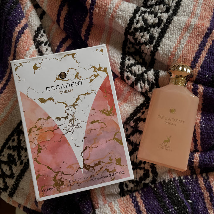 Decadent Dream perfume bottle and packaging on a patterned fabric background