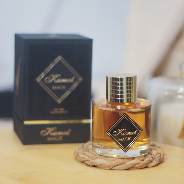 Perfume bottle with 'Kismet Magic' packaging on a wooden surface