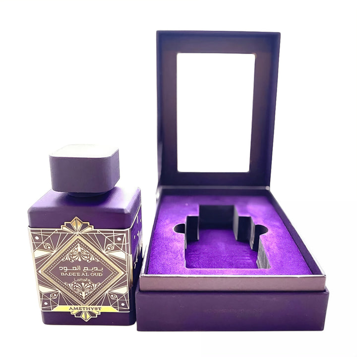 Purple candle with decorative label next to an open purple box on a white Bade'e Al Oud Amethyst Lattafa Perfumes for women and men
background