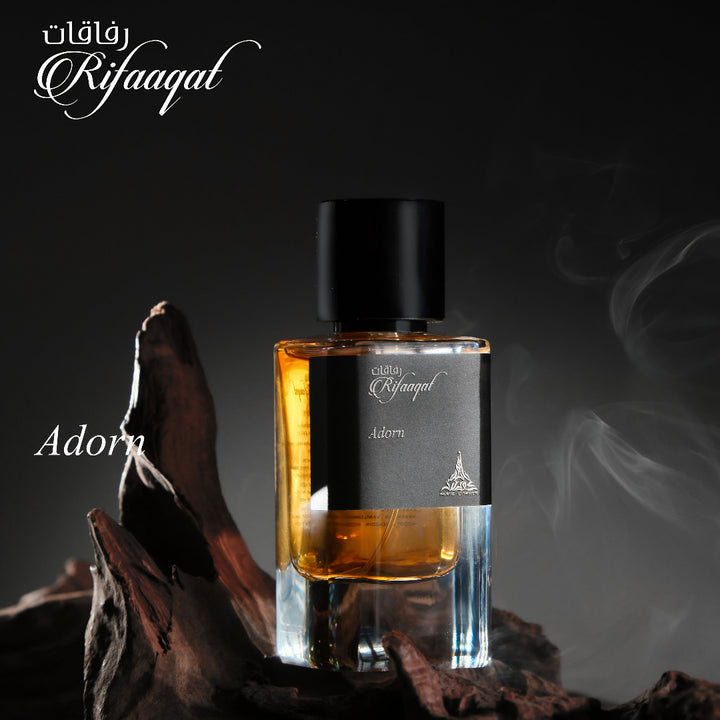 Perfume bottle labeled 'Adorn' by Rifaqat on a dark background with smoke effect.