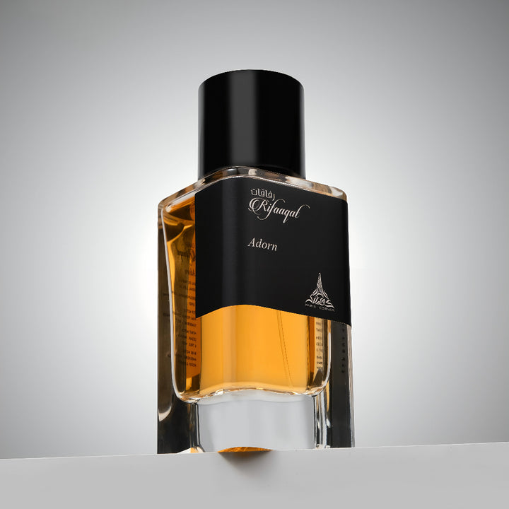 Perfume bottle with black cap and gold body on a gray background Rifaaqat Adorn 85ml EDP – Unisex Woody Chypre Perfume by Paris Corner