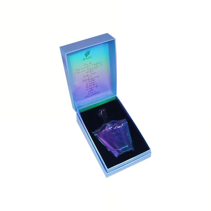 Small glass bottle with a colorful label inside an open box on a white background afnan electric turathi perfume