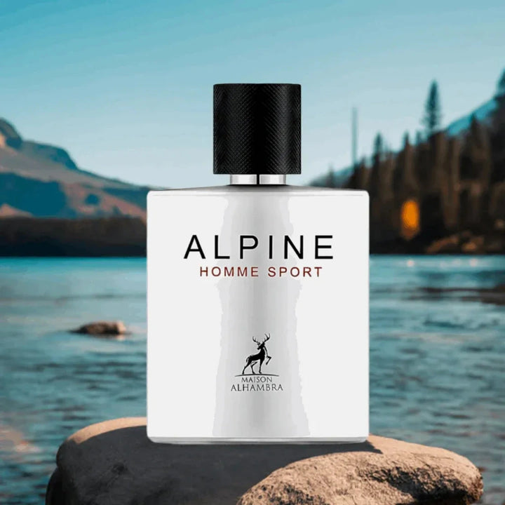 Perfume bottle labeled 'Alpine Homme Sport' on a rock with a scenic background of water and mountains.