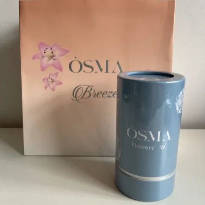 Blue cylindrical product with 'OSMA' branding next to a pink 'OSMA Breeze' bag on a light background