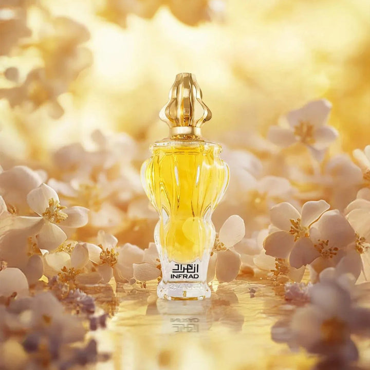 Perfume bottle with gold cap and clear body surrounded by white flowers on a yellow background
