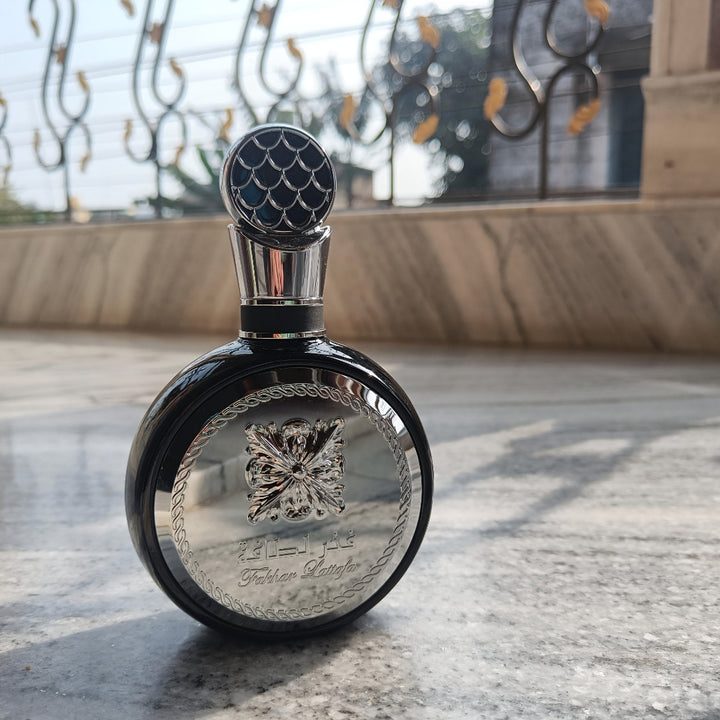 Decorative bottle Lattafa fakhar silver  with intricate design on a marble surface 