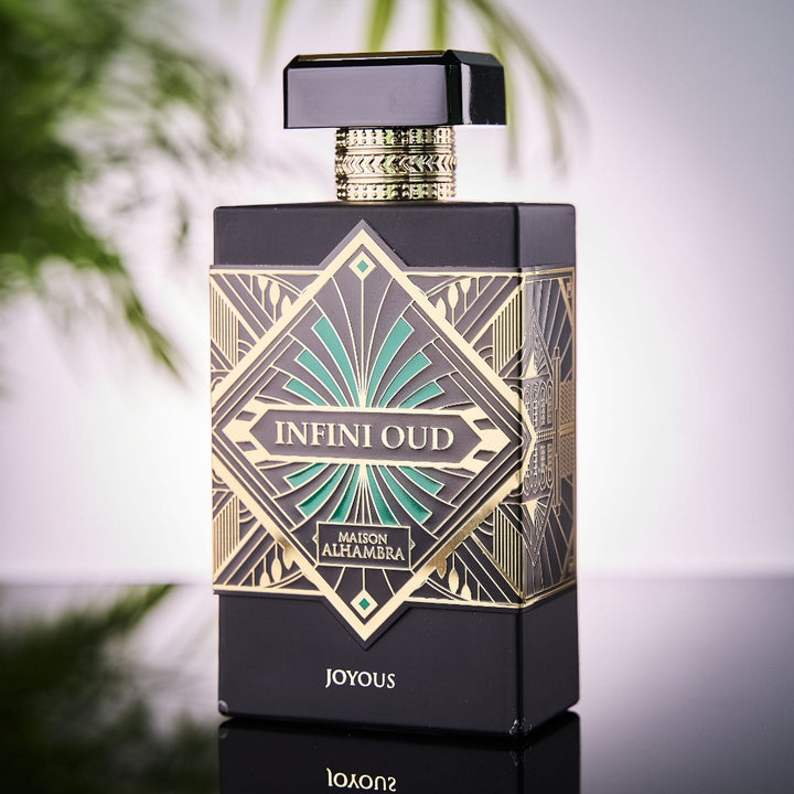 Perfume bottle with intricate design and 'Infini Oud' branding on a reflective surface.