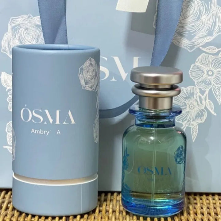 OSMA perfume bottle and cylindrical container on a textured surface with a decorative background