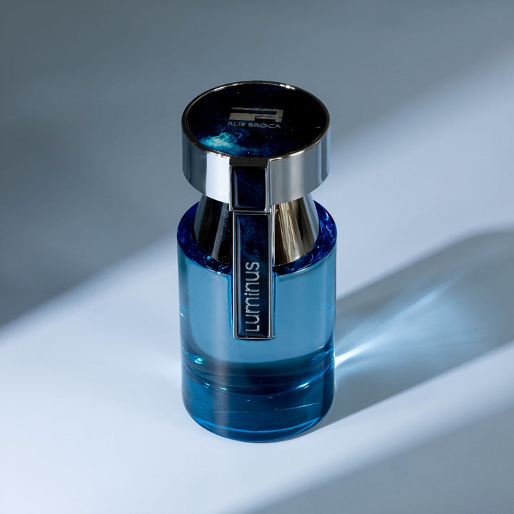 Blue bottle with silver cap on a gray background Luminus Pour Homme Rue Broca for men