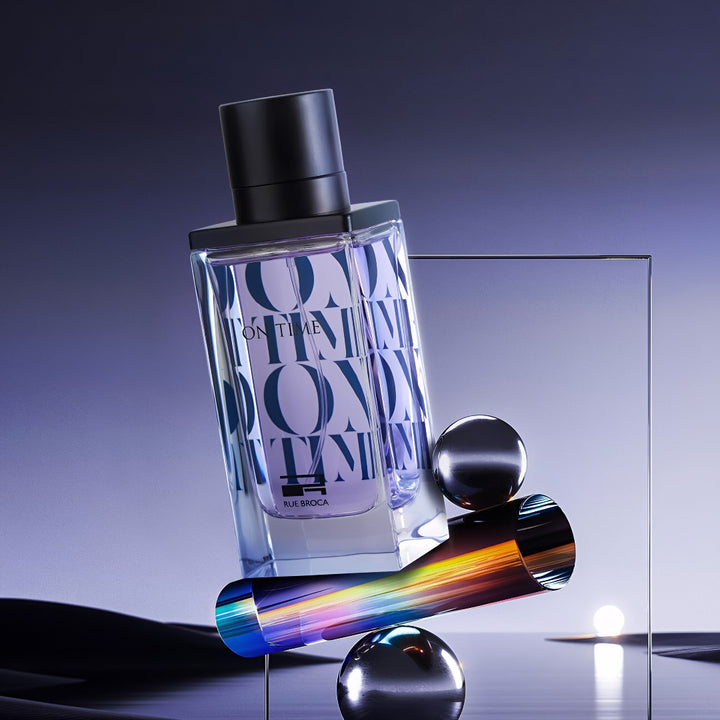 On Time pour Homme Rue Broca Perfume bottle with a colorful cylindrical object on a reflective surface