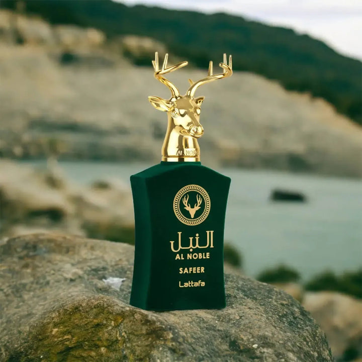 Green perfume bottle with gold deer design on a rock with a mountainous background