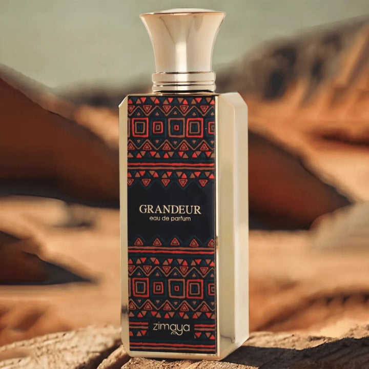 Perfume bottle with geometric pattern and 'Grandeur' branding on a blurred natural background